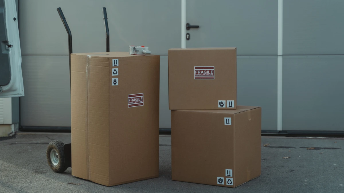 Cajas de cartón de envíos apiladas junto a una carretilla