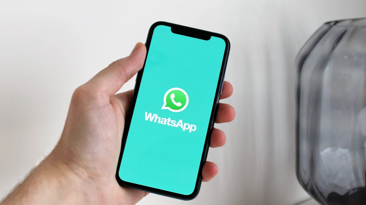 Mano sujetando un móvil con el logotipo de WhatsApp en la pantalla